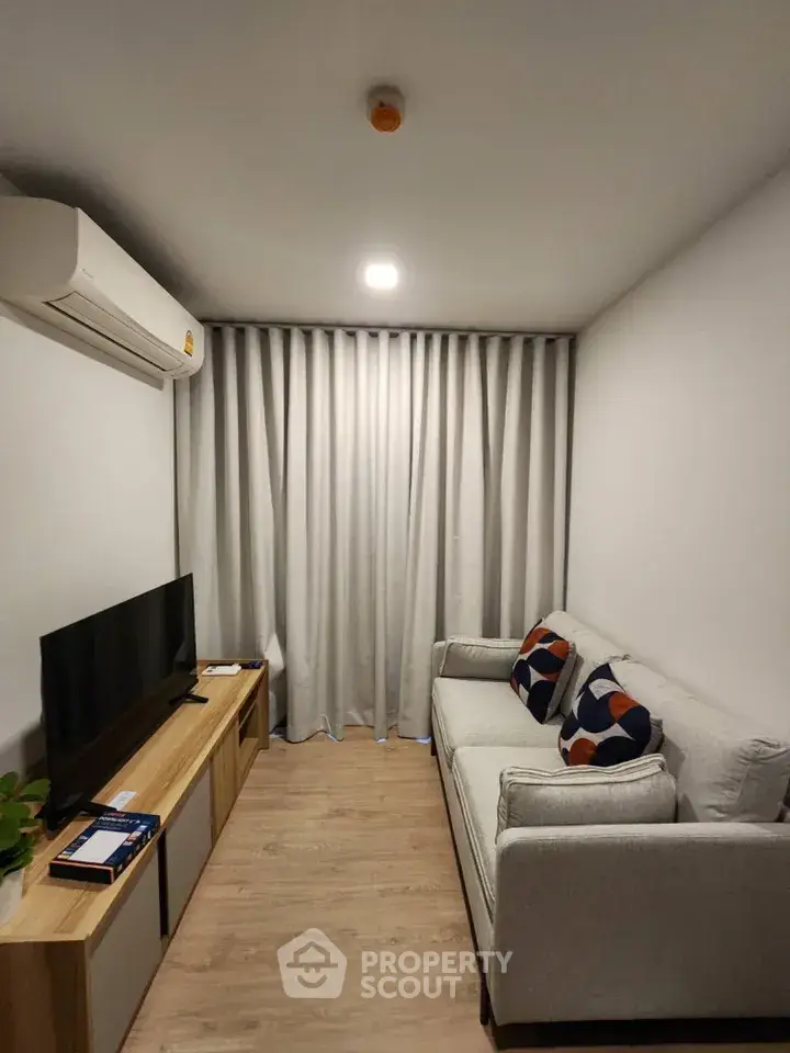 Cozy modern living room with sleek furniture and air conditioning, perfect for relaxation.