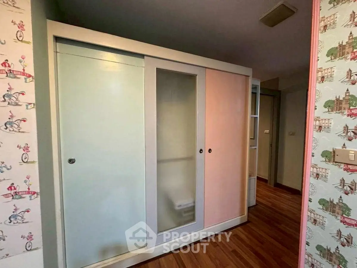 Charming interior with colorful sliding door wardrobe and vibrant wallpaper accents.