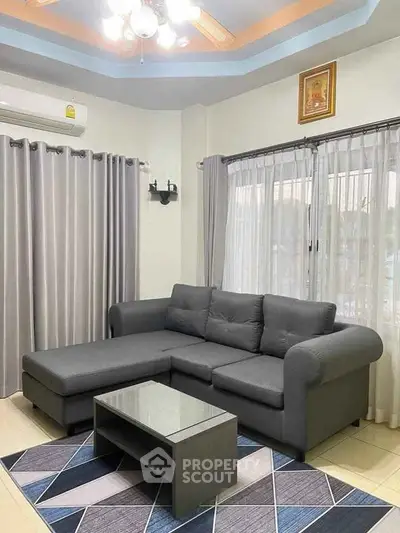Stylish living room with modern gray sectional sofa and elegant curtains.