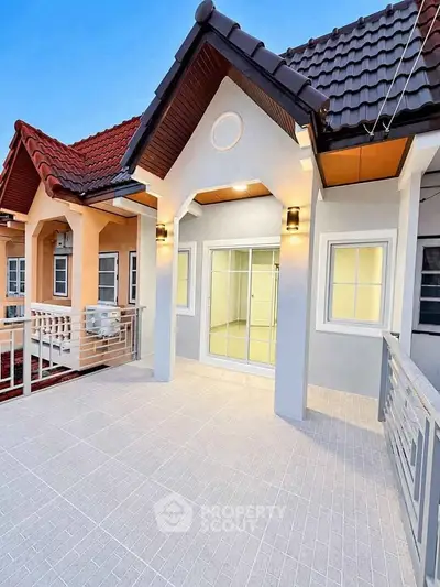 Charming townhouse exterior with modern lighting and tiled balcony, perfect for cozy living.