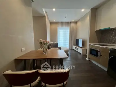 Modern living room with open kitchen, featuring stylish furniture and sleek appliances.