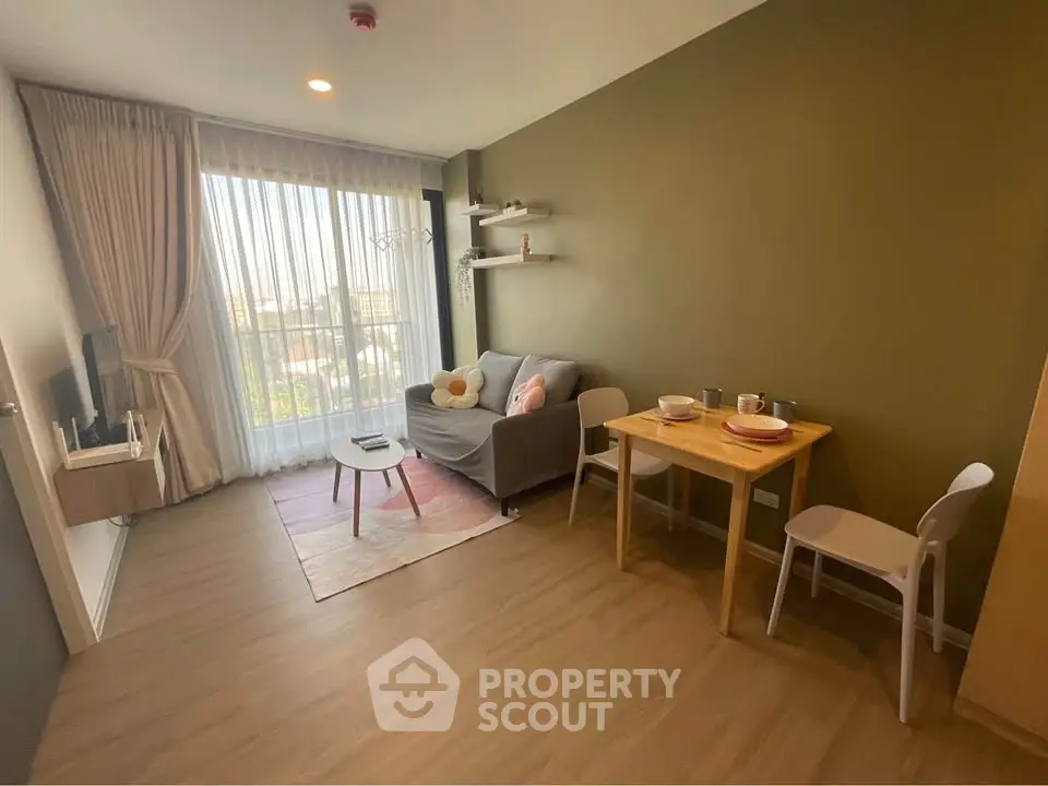 Modern living room with cozy sofa, dining table, and large window offering natural light.