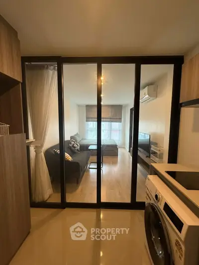 Modern apartment with glass partition, cozy living area, and in-unit washing machine.