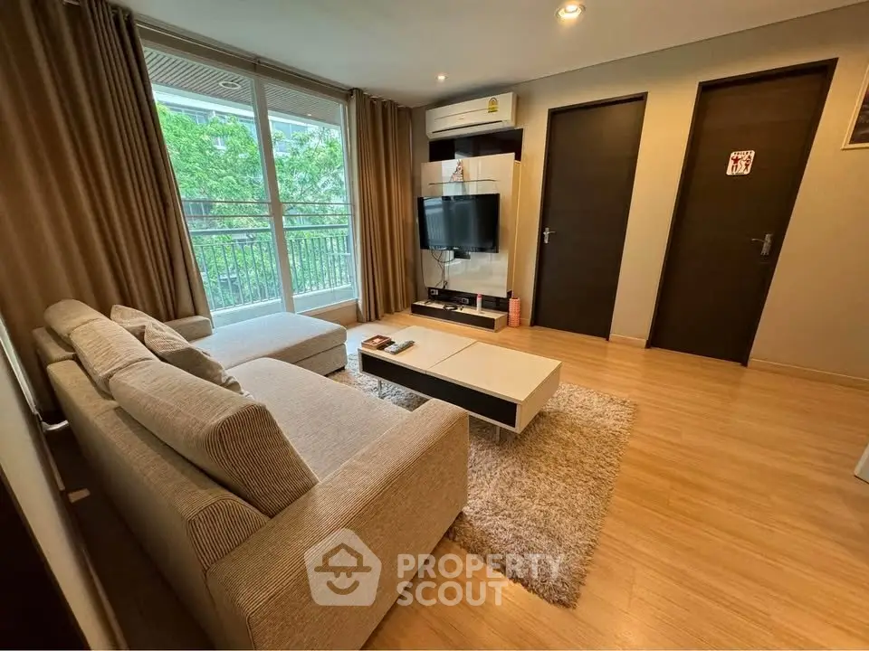 Modern living room with cozy sofa, flat-screen TV, and balcony view in stylish apartment.