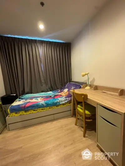 Cozy bedroom with modern desk and stylish bedding in a well-lit apartment.