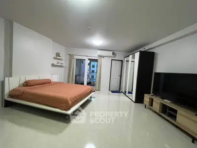 Spacious modern bedroom with sleek furniture and large TV, perfect for comfort and relaxation.
