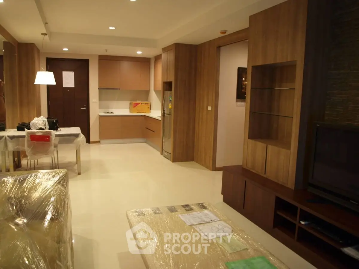 Spacious modern living room with open kitchen layout and stylish wooden cabinetry.