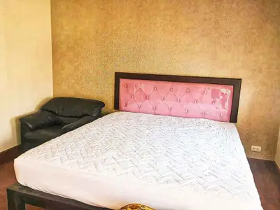 Cozy bedroom with elegant pink headboard and plush armchair, perfect for relaxation.