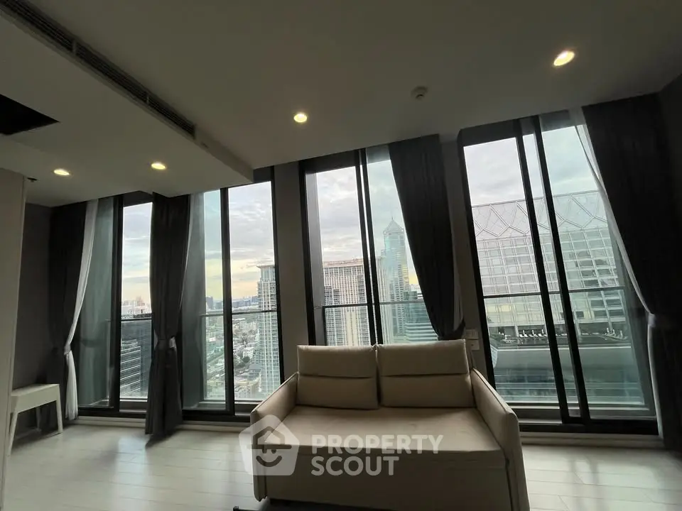 Luxurious living room with floor-to-ceiling windows offering stunning city views in a modern high-rise apartment.