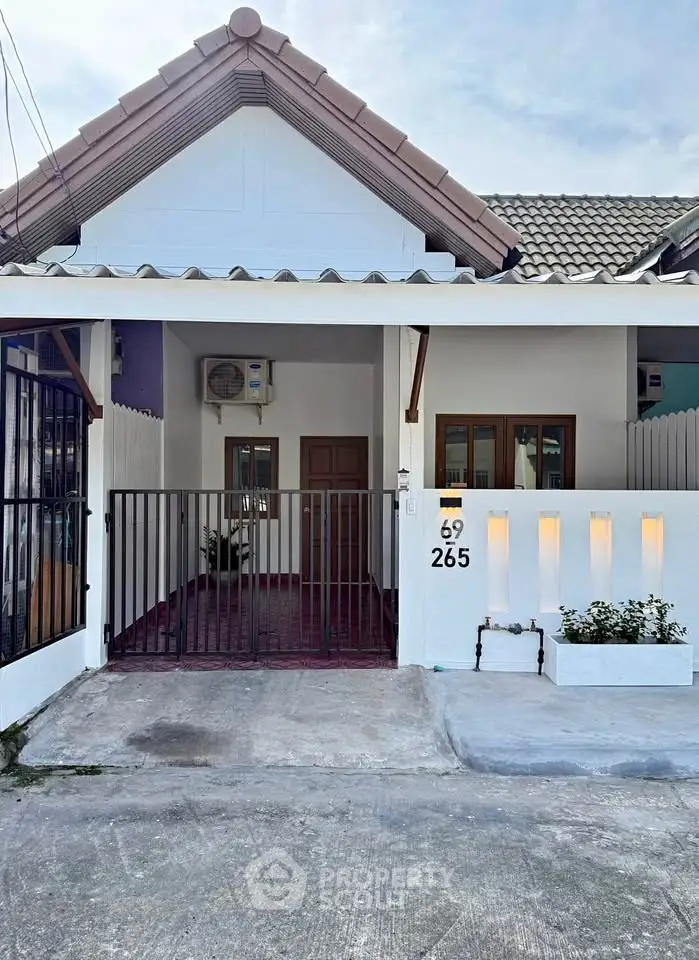 Charming single-story house with gated entrance and tiled roof, perfect for cozy living.