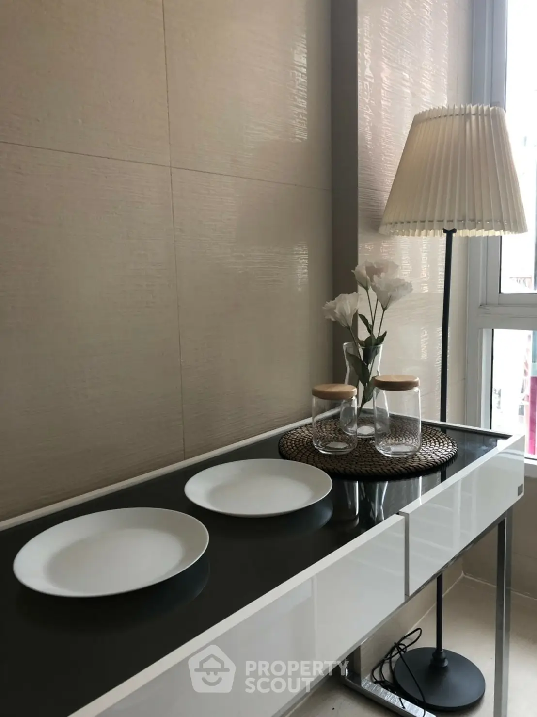 Modern interior with sleek console table, elegant lamp, and decorative plates in a stylish setting.