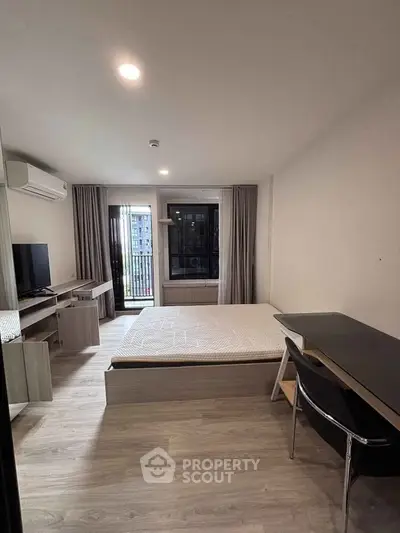 Modern bedroom with sleek furniture and large window offering city view