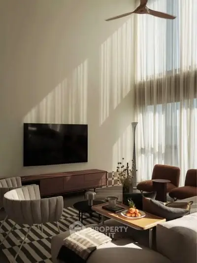 Luxurious living room with high ceilings, modern furniture, and large TV, bathed in natural light.
