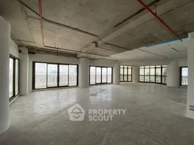 Spacious open-plan interior with large windows and concrete flooring, ideal for customization.