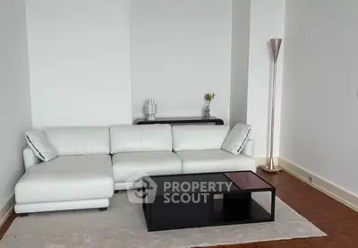 Modern living room with white leather sofa and sleek black coffee table on a cozy rug.