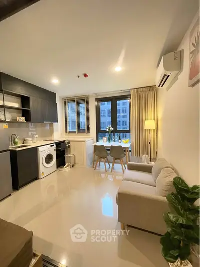 Modern open-layout living room with kitchen, featuring washing machine and dining area, ideal for urban living.