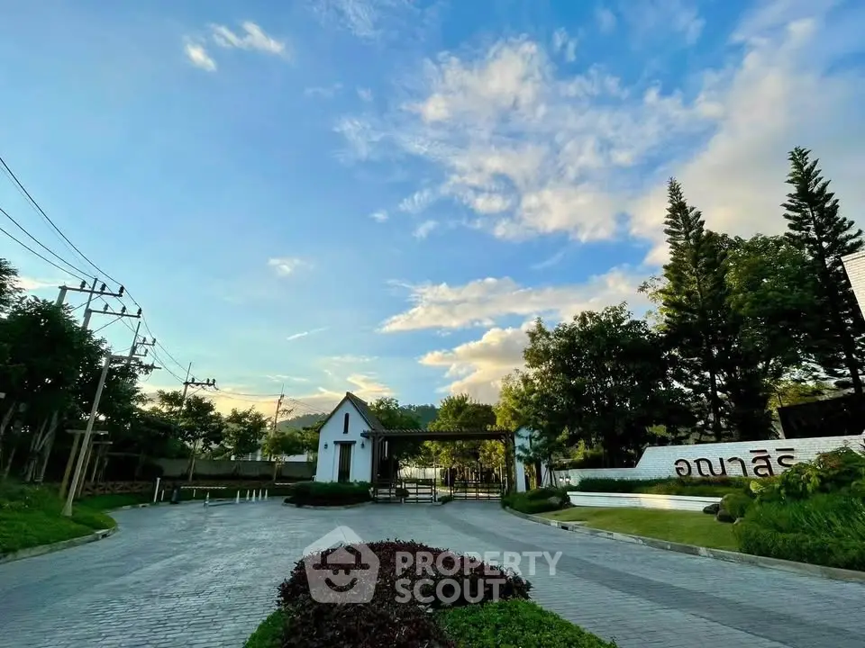 Stunning entrance of a modern residential complex with lush greenery and clear blue skies.