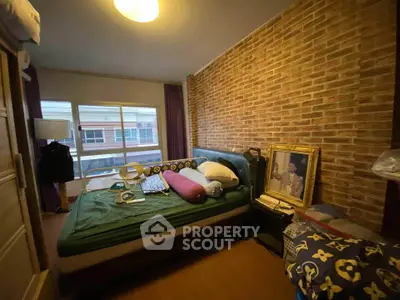 Cozy bedroom with exposed brick wall and large window for natural light.
