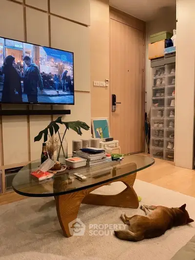 Cozy living room with modern decor, glass coffee table, and wall-mounted TV, perfect for relaxation.