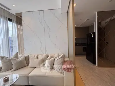 Luxurious modern living room with elegant marble wall and cozy beige sofa, adjacent to sleek kitchen area.