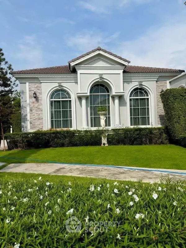 Elegant single-story house with manicured lawn and classic architectural design.