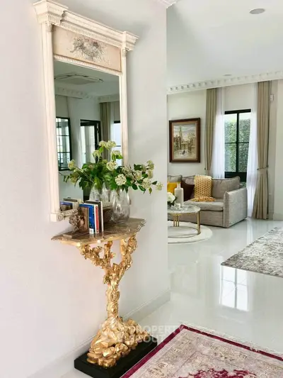 Elegant living room with luxurious decor, featuring a gold ornate console table and large mirror, exuding sophistication.