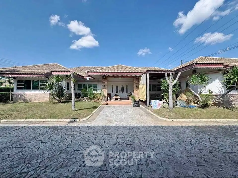 Charming single-story home with spacious driveway and lush landscaping under a clear blue sky.