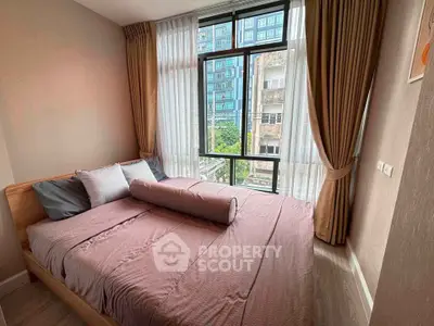 Cozy bedroom with large window offering city view, featuring elegant curtains and stylish bedding.