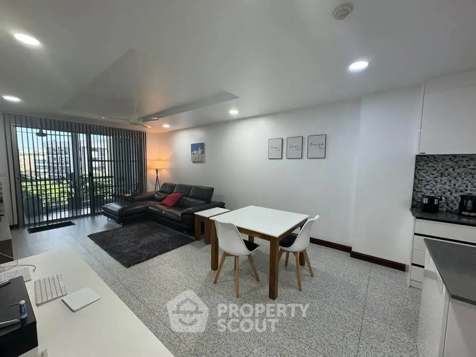 Spacious modern living room with open kitchen and balcony view, perfect for urban living.