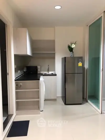 Modern kitchen with sleek appliances and minimalist design, featuring a fridge and washing machine.