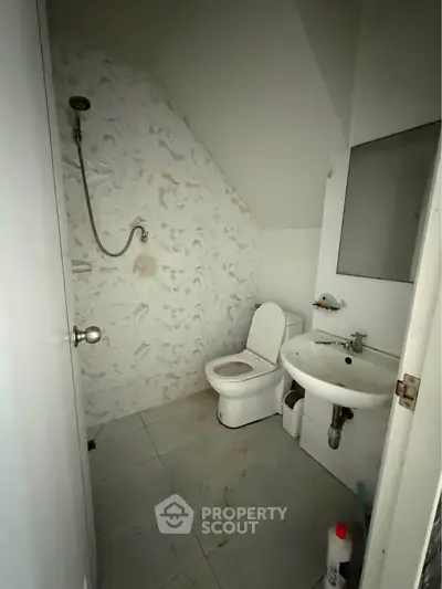 Compact bathroom with shower, toilet, and sink in a modern minimalist design.
