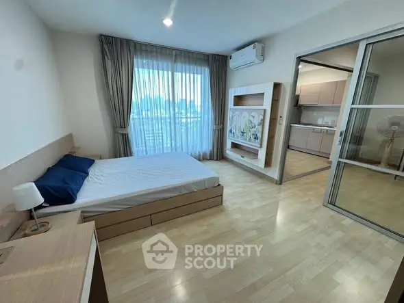 Spacious bedroom with modern decor and large window in a stylish apartment.