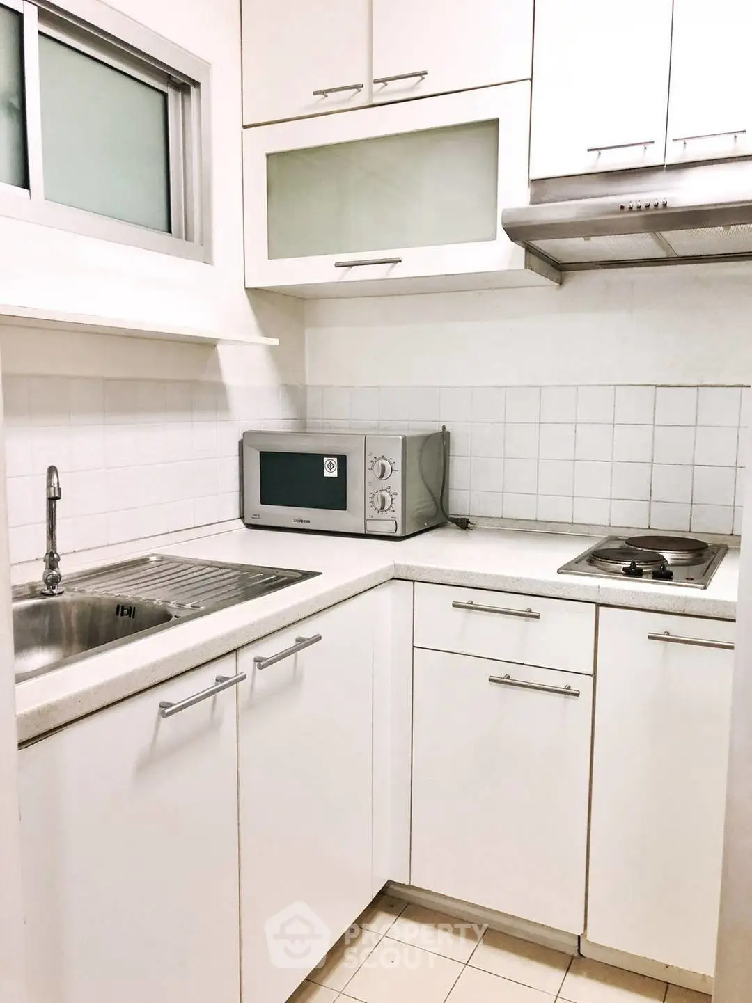 Compact modern kitchen with white cabinetry and built-in appliances in a cozy apartment.
