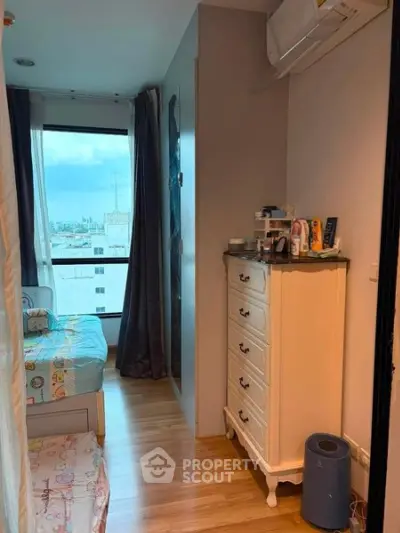 Charming bedroom with city view, featuring wooden flooring and elegant dresser.