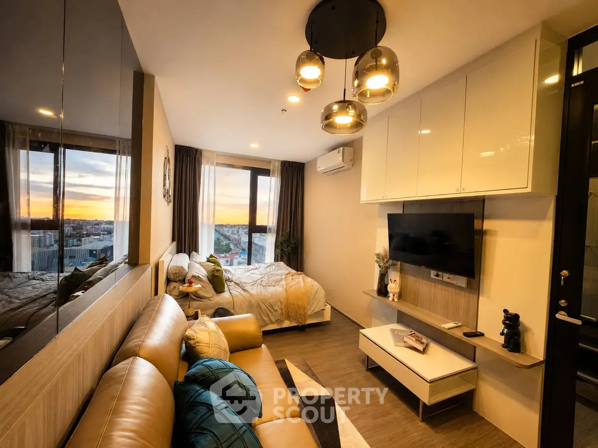 Modern studio apartment with cozy living area and stunning city view at sunset.