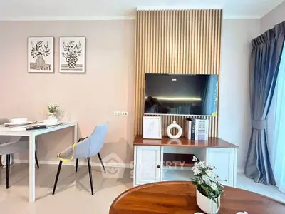 Modern living room with stylish decor and natural light, featuring a TV and dining area.