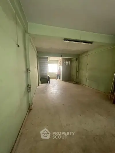 Spacious interior with potential for renovation, featuring large windows and open layout.