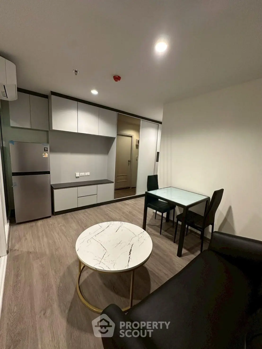 Modern living room with sleek furniture and open layout, featuring a stylish marble coffee table and dining area.