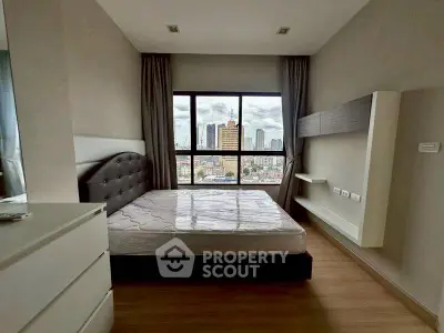Modern bedroom with city view, featuring a large window and sleek furnishings.