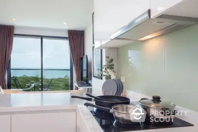 Modern kitchen with sleek design and stunning ocean view from large windows.