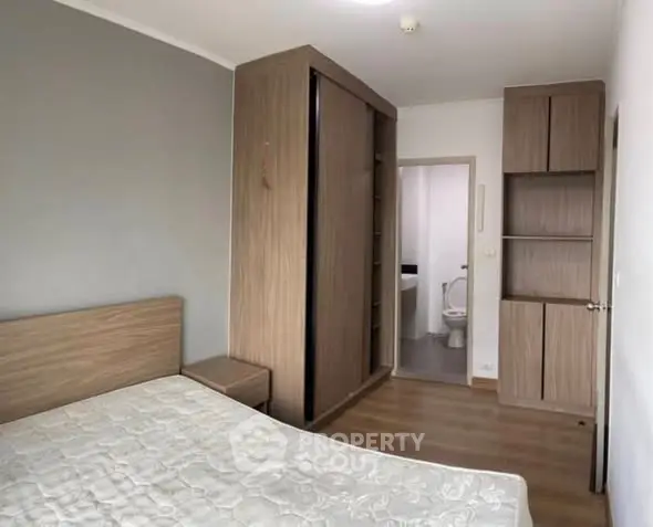 Spacious bedroom with ensuite bathroom and modern wooden furniture.