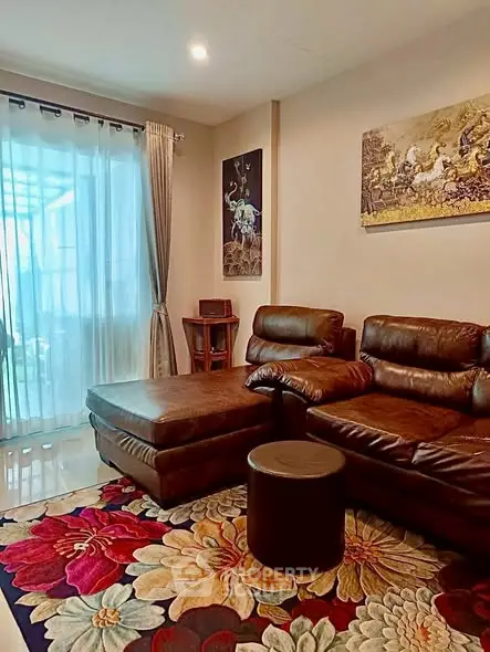 Cozy living room with leather sofa and floral rug, perfect for relaxation.