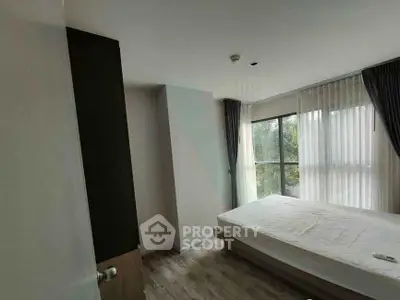 Spacious bedroom with large windows and natural light in modern apartment.