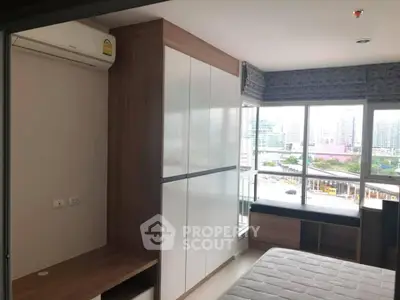 Modern bedroom with large windows and city view, featuring built-in wardrobe and air conditioning.
