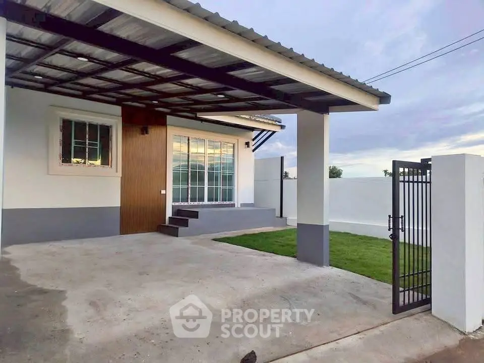 Modern single-story home with gated driveway and lush green lawn.