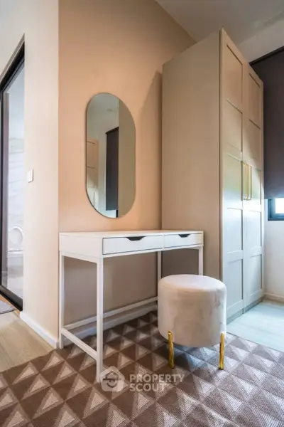Stylish bedroom corner with modern vanity and plush stool in elegant apartment.