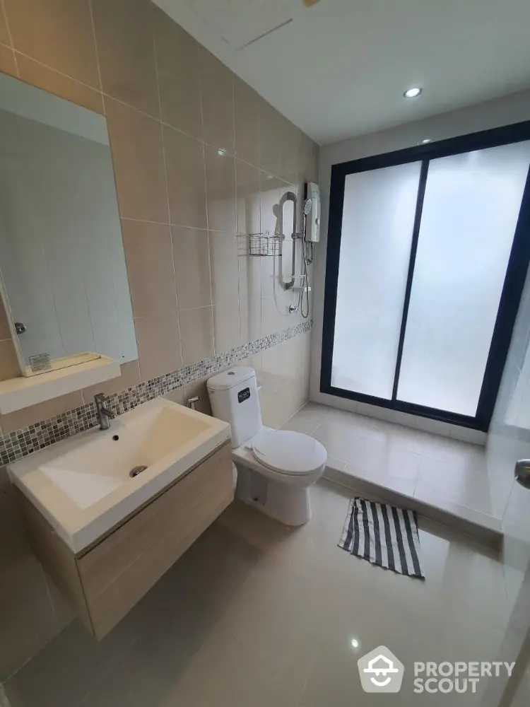 Modern bathroom with sleek fixtures and large frosted glass window