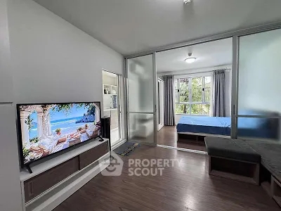 Modern living room with TV and view into cozy bedroom