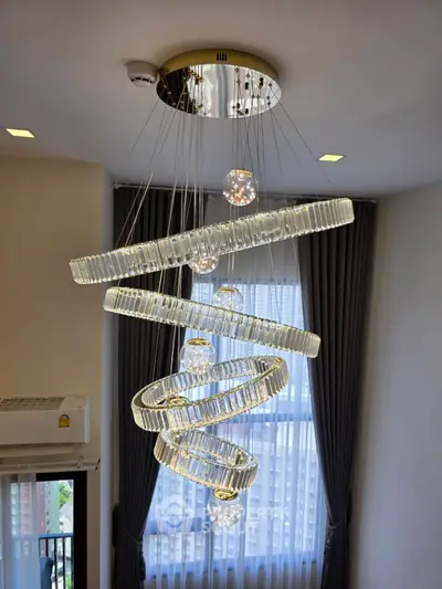 Elegant spiral chandelier in modern living room with large window and city view.