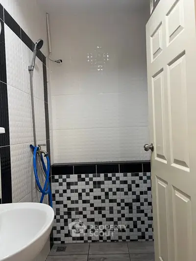 Modern bathroom with stylish black and white tile design and shower area.